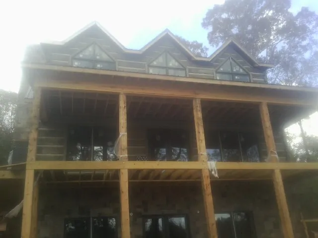 Dormers and porch framing on a large log home under construction — Roof Coating work by our crew in Glen Ellyn