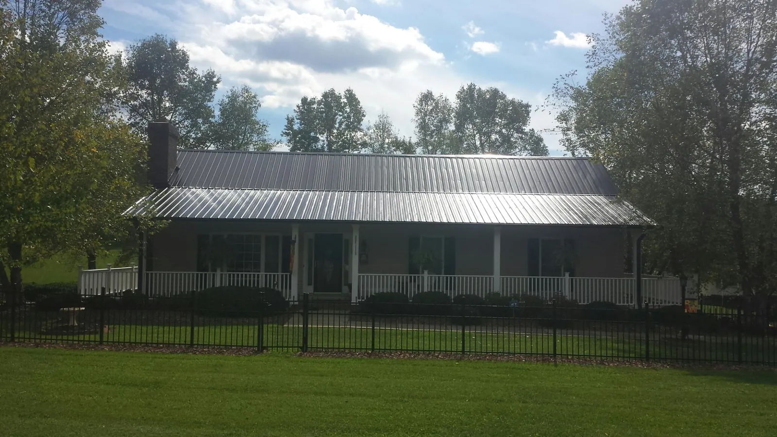 Gray metal roof on a brick ranch with a full width front porch — Gutter Guard Installation work by our crew in Glen Ellyn