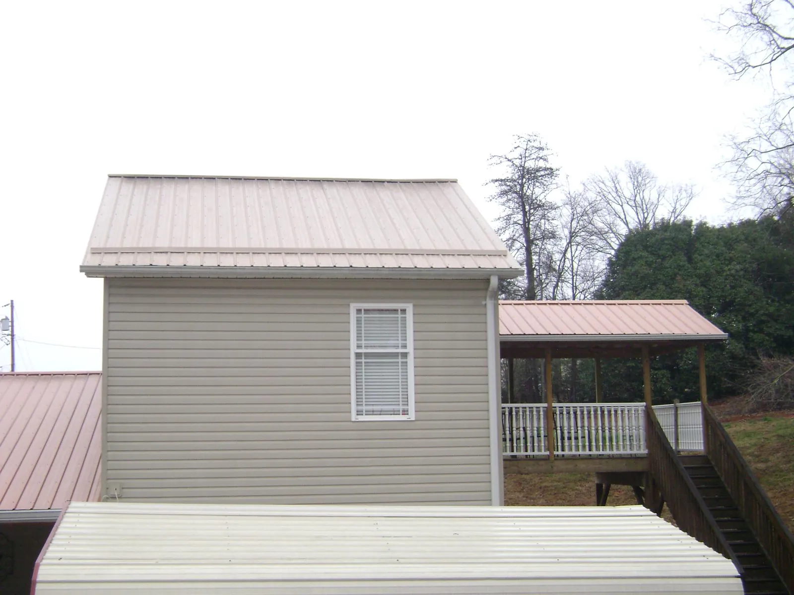 Tan metal roofs on a two story addition and attached porch, from a Roof Replacement job in Glen Ellyn