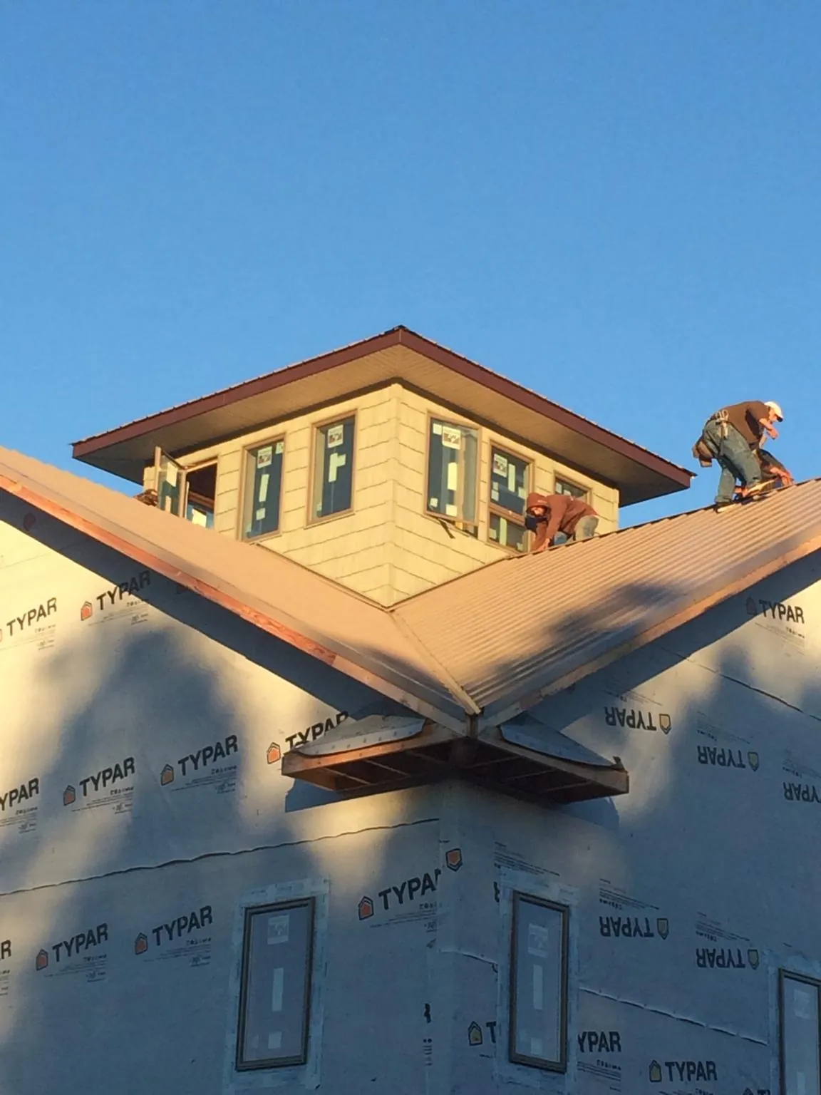 Roofers working around a rooftop cupola on a new metal roof at sunset — Roof Waterproofing in Glen Ellyn by Roofing Brothers